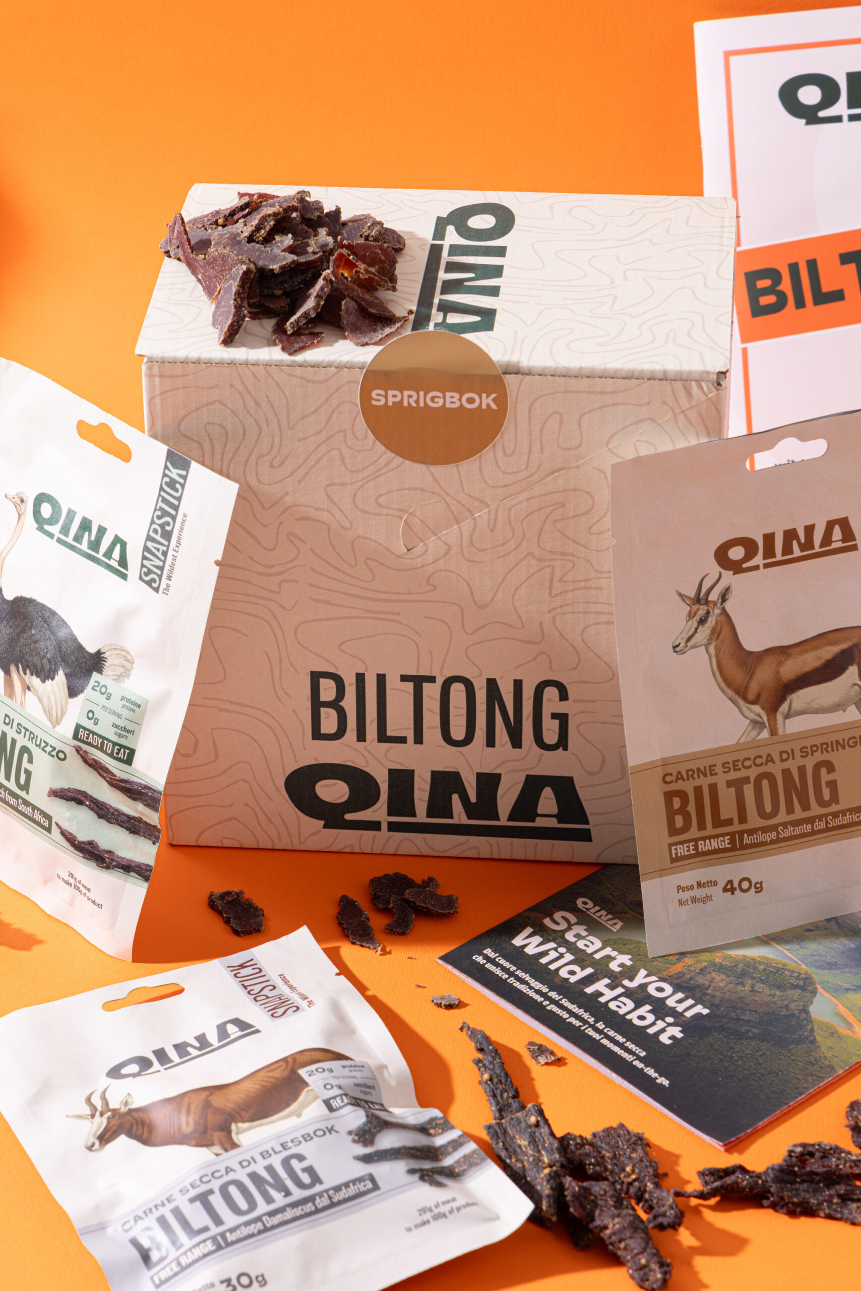 A box of QINA snacks, and several other flavors of Snapsticks shown together